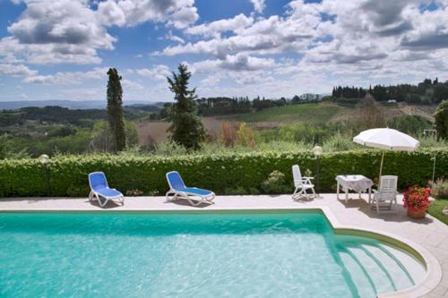 basen z krzesłami, stołem i parasolem w obiekcie Monolocale il vecchio fienile w mieście San Gimignano