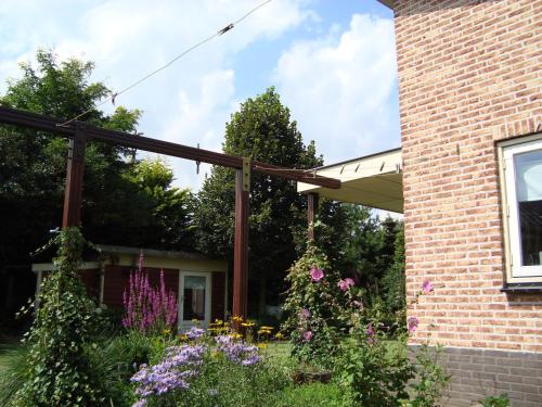 a pergola attached to a brick house with flowers at Vakantiehuis Petrarca in Putten