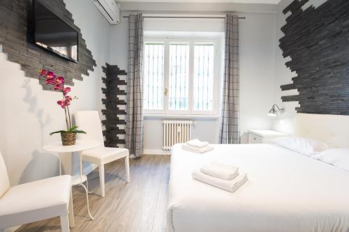 - une chambre blanche avec 2 lits, une table et des chaises dans l'établissement Royal House Vaticano, à Rome