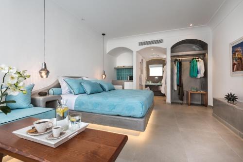 a bedroom with a blue bed and a living room at Elements of Caldera Suites in Akrotiri