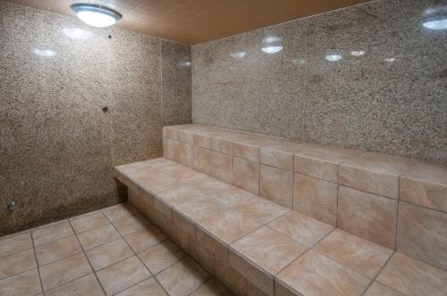 a bathroom with a shower with brown tiles at Governors Suites Hotel Oklahoma City Airport Area in Oklahoma City