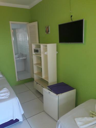 a room with a green wall with a tv on the wall at Hotel Pousada Papaya Verde in Salvador