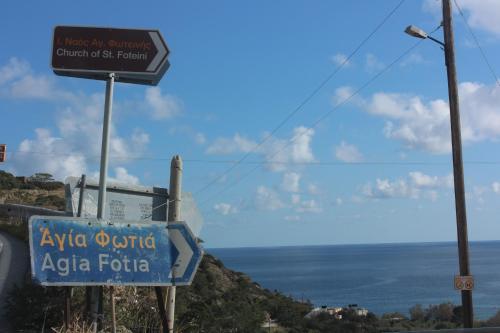 a sign on the side of a road next to the ocean at Aaron Studios Apartments in Agia Fotia