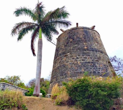 a palm tree standing next to a brick tower at Sand Castle on the Beach - Adults Only in Frederiksted