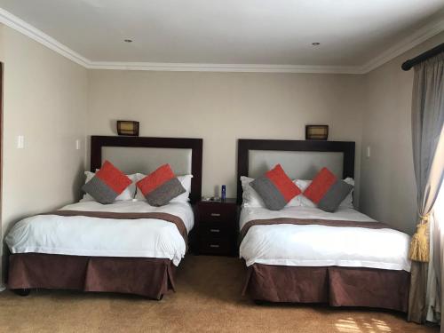 a bedroom with two beds with red and grey pillows at Ebandla Hotel & Conference Centre in Ballito