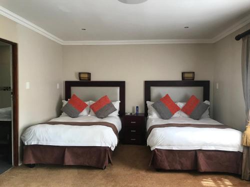 a bedroom with two beds with red and grey pillows at Ebandla Hotel & Conference Centre in Ballito