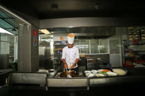 a chef standing in a kitchen preparing food at Lavendish Hills Kandy in Kandy