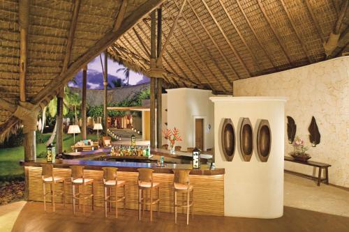 a bar in a resort with some chairs and a table at Zoëtry Agua Punta Cana, Punta Cana, Dominican Republic in Punta Cana