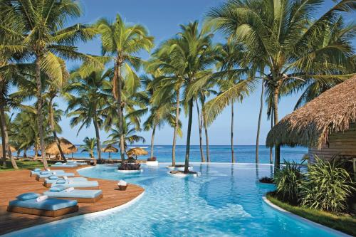 - une piscine à débordement avec des chaises longues et des palmiers dans l'établissement Zoetry Agua Punta Cana - All Inclusive, à Punta Cana