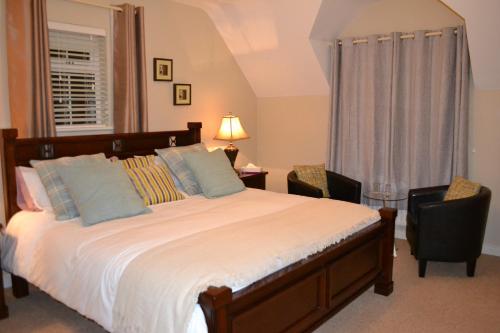 um quarto com uma cama, 2 cadeiras e uma janela em Woodview Bed & Breakfast. em Letterkenny