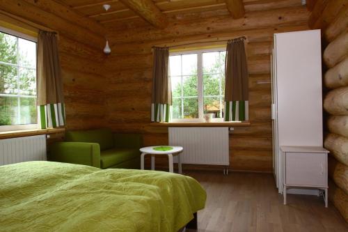 a bedroom with a bed and a chair and windows at Asvejos slenis in Sužionys