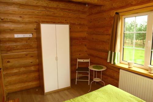a bedroom with a cabinet and a table and a window at Asvejos slenis in Sužionys