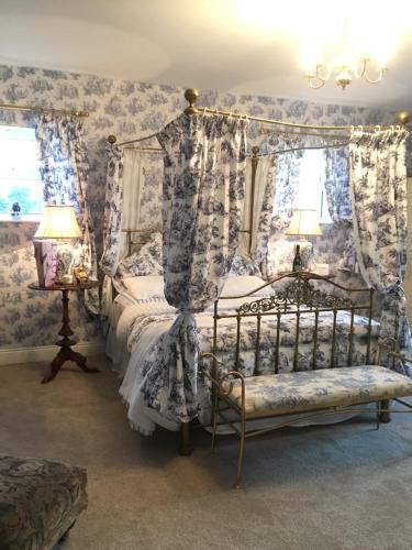 a bedroom with a canopy bed with blue and white wallpaper at Rossmanagher House in Bunratty