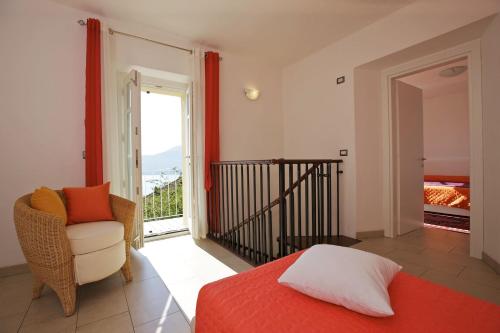sypialnia z łóżkiem i krzesłem oraz balkon w obiekcie La Tranquillità w mieście Oggebbio