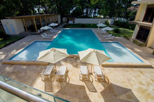 a swimming pool with chairs and umbrellas at Caribbean Diamond Boutique Hotel in Sosúa