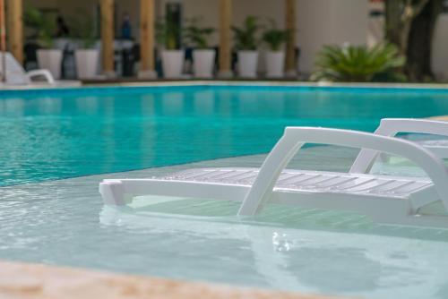 two white chairs sitting in a swimming pool at Caribbean Diamond Boutique Hotel in Sosúa