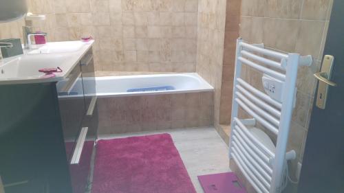 ein Badezimmer mit einer Badewanne und einem Waschbecken in der Unterkunft Les Giroflées in Coubon