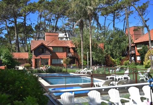 a swimming pool with white chairs and a house at La Posta de Cariló in Carilo