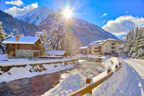 a resort in the snow with a river and mountains at The Twins Apartment - Champoluc in Champoluc