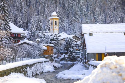 a snow covered village with a clock tower in the distance at The Twins Apartment - Champoluc in Champoluc