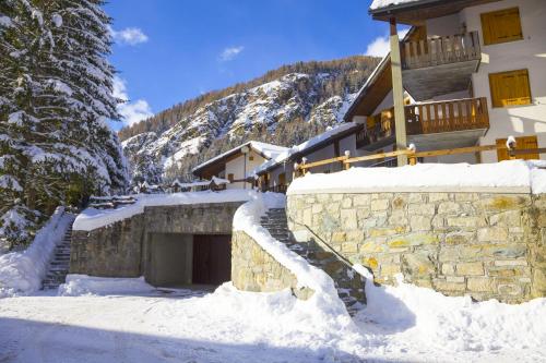 a snow covered building with a garage in front of it at The Twins Apartment - Champoluc in Champoluc