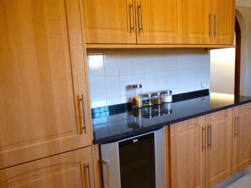 a kitchen with wooden cabinets and a black counter top at Villa Tara Christina in Carvoeiro