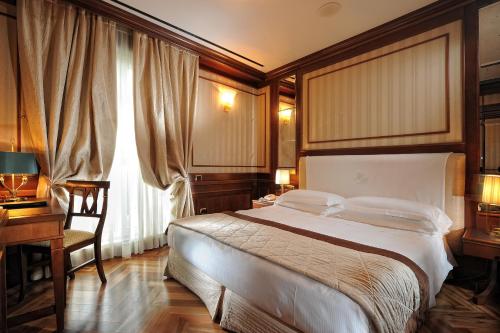 a bedroom with a large bed and a desk and a window at Hotel Manzoni in Milan