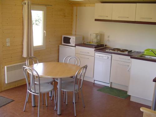 een keuken met een tafel en stoelen in een kamer bij Le Chalets du lac de Ganivet in Ribennes