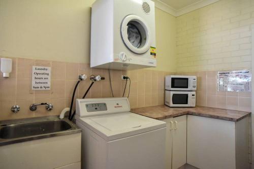 a kitchen with a microwave and a sink at The Crossing Motel in Junee