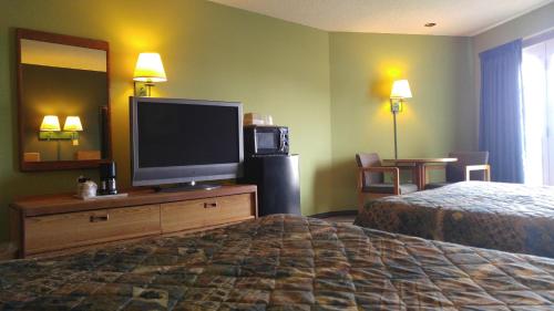 a hotel room with a flat screen tv and a bed at Harbor Lights Lodge in Kewaunee