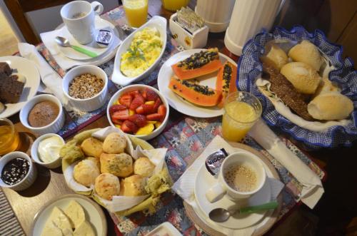 a table topped with plates of breakfast foods and drinks at Tirol Chalés in Monte Verde