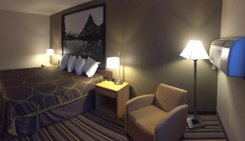 a hotel room with a bed and a chair at Super 8 by Wyndham Dillon in Dillon
