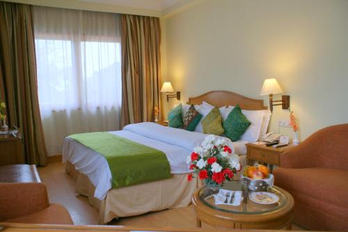 a hotel room with a bed and a table with flowers at Ritz Plaza in Amritsar