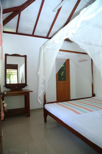 a bedroom with a bed with a mirror and a dresser at Gihan Guesthouse in Mirissa