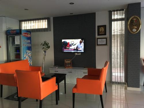 a dining room with orange chairs and a tv on a wall at Mutado Hotel in Antalya