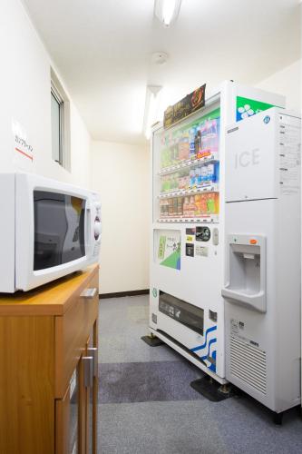 a white refrigerator next to a desk with a microwave at Hotel Iidaya in Matsumoto