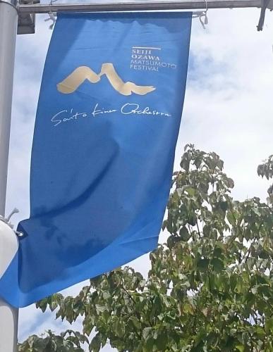 a blue banner hanging from a pole in front of a tree at Hotel Iidaya in Matsumoto