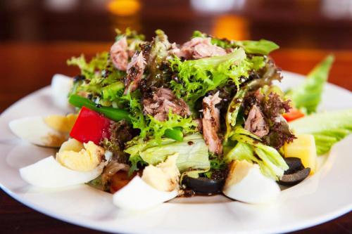 a white plate with a salad on a table at Hello Cambodia Boutique in Siem Reap