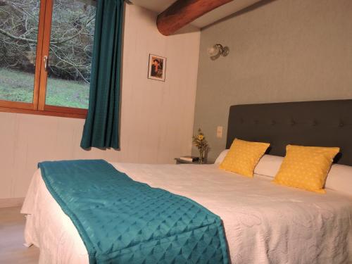 a bedroom with a bed with yellow pillows and a window at Le Moulin du Barthas in Montredon-Labessonnié