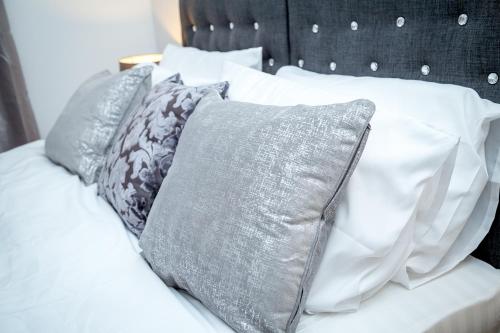łóżko z białą pościelą i poduszkami w obiekcie Luxuriant Apartments w mieście Northampton