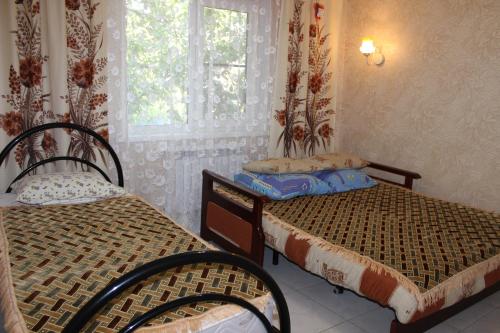 2 camas en una habitación con ventana y 2 sillas en Holiday Home, en Yeysk