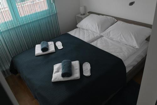 a bedroom with a bed with towels and slippers at Oaza Apartman Zagreb Arena 1 in Zagreb