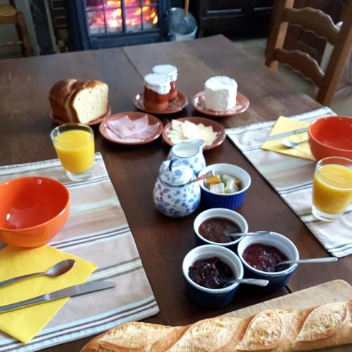 een houten tafel met kommen eten en sinaasappelsap bij Les rives de Champagne in Courceroy