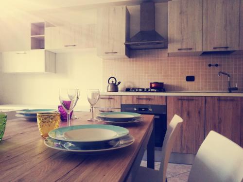 eine Küche mit einem Holztisch mit Tellern und Weingläsern in der Unterkunft Casa Maresole in Diano Marina