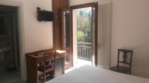 a bedroom with a bed and a desk and a balcony at Acquacheta Valtancoli in San Benedetto in Alpe