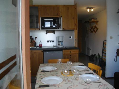 una cocina con una mesa con platos y vasos. en Les Cretets, en Les Rousses