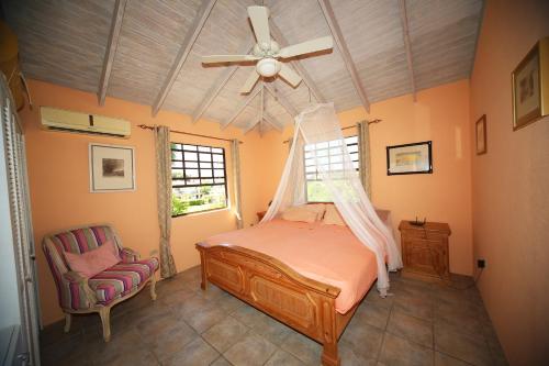 a bedroom with a bed with a ceiling fan and a chair at Eumelvilla in Saint James