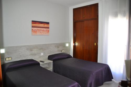 a bedroom with two beds and a wooden door at Hotel Congra in Pilar de la Horadada