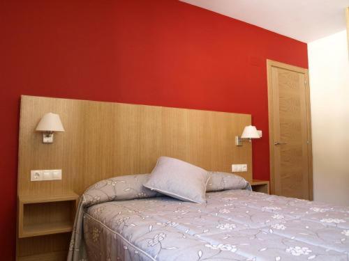 a bedroom with a bed and a red wall at Aparthotel Peña Telera Resort in El Pueyo de Jaca
