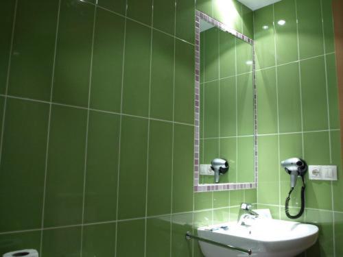 Baño verde con lavabo y espejo en Aparthotel Peña Telera Resort, en El Pueyo de Jaca